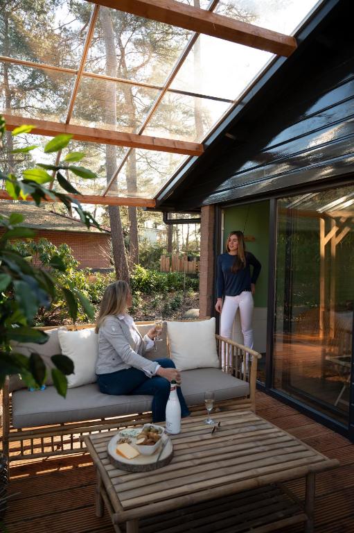two women sitting on a bench on a patio at ZEN-bungalow NO 1 met sauna en hottub in Rheezerveen