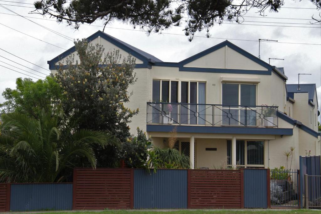a house with a blue fence in front of it at Sea Breeze on the Esplanade in Lakes Entrance
