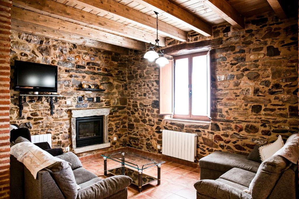sala de estar con pared de piedra con sofás y chimenea en Casa El Habanero II en Destriana