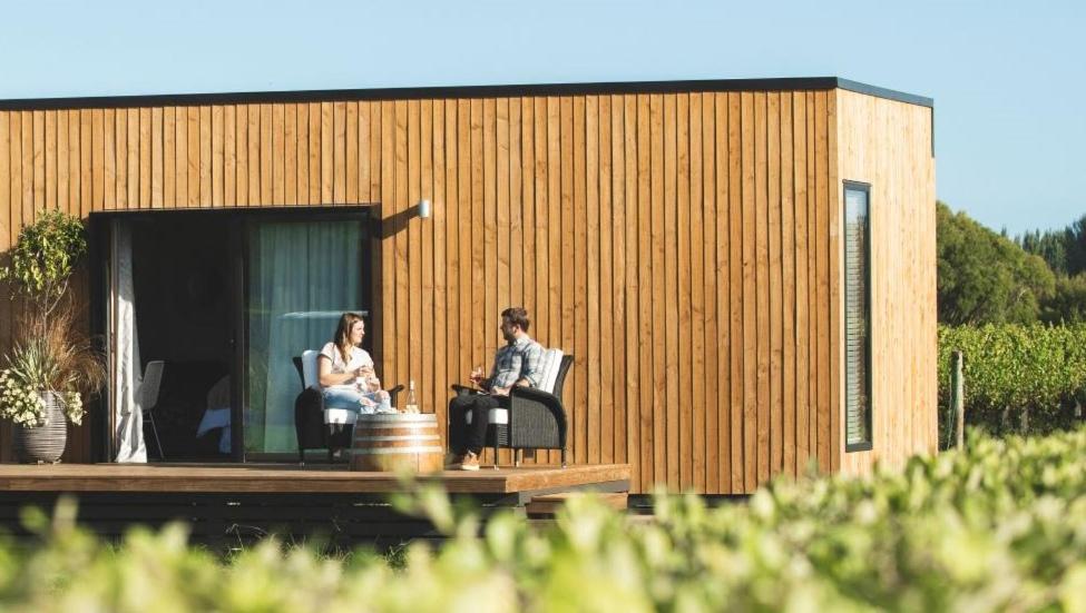 a couple sitting on the porch of a tiny house at Matawhero Wines in Gisborne