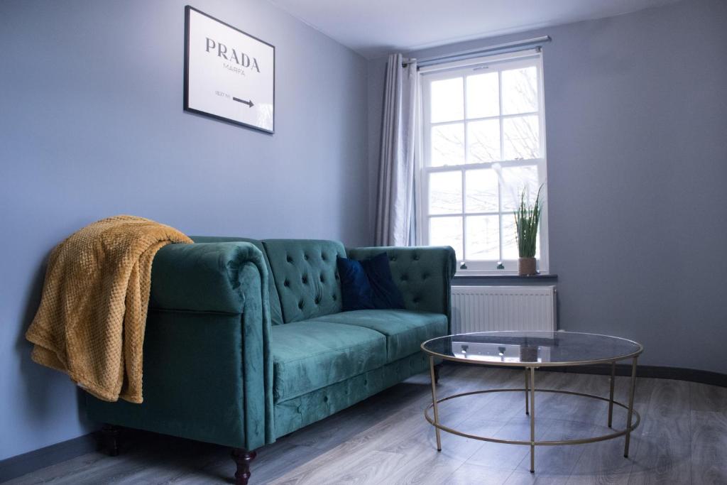 a living room with a green couch and a glass table at The Countryman Hideaway - Funky Loft Room in Gillingham