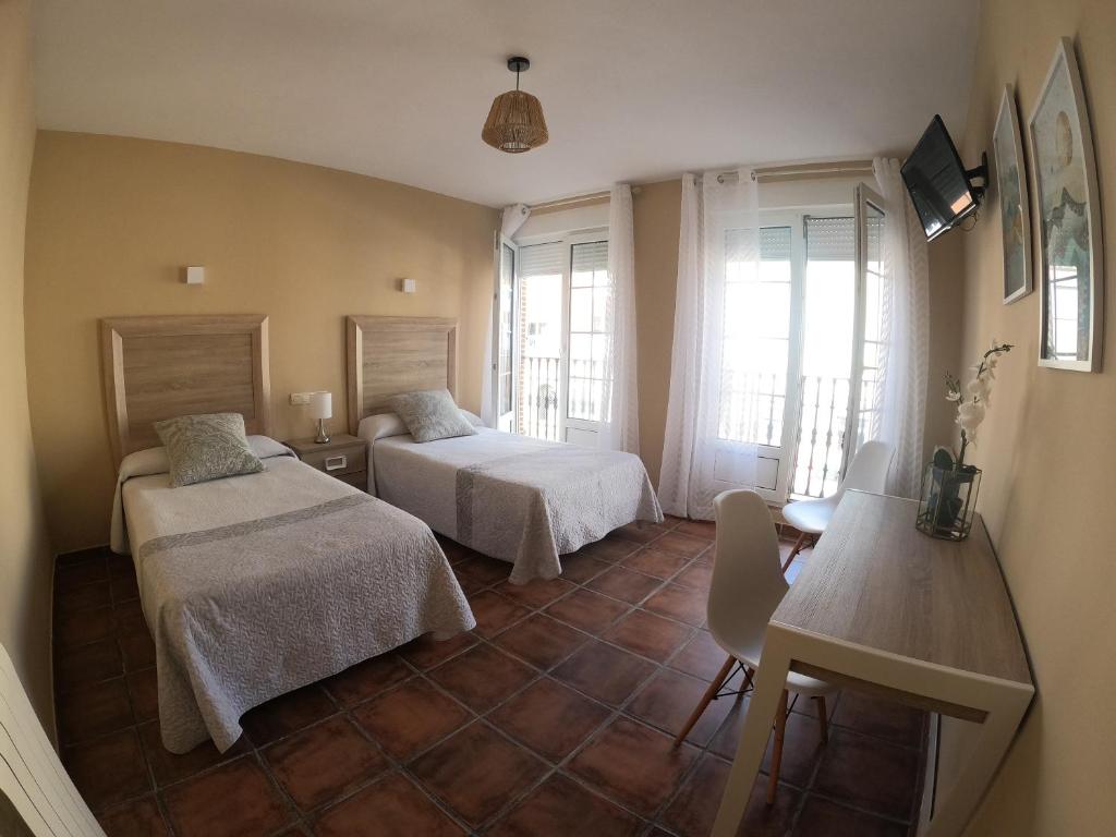 a bedroom with two beds and a table and a table at Hostal Santiago in Carrión de los Condes