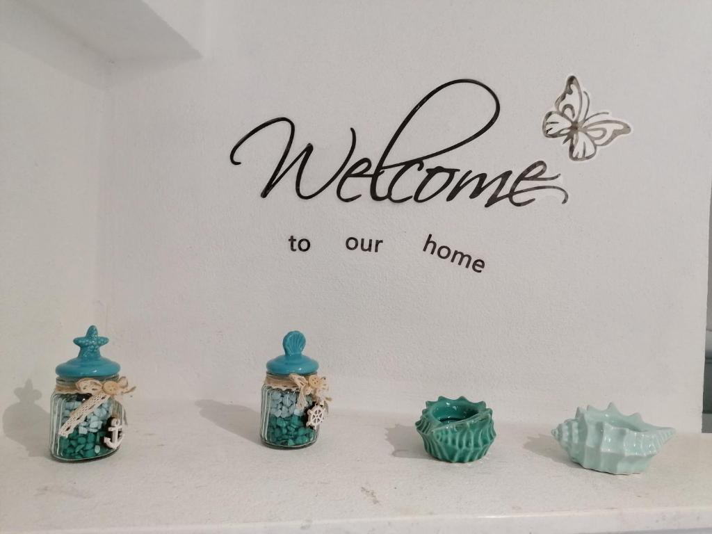 a welcome to our home sign on a wall with three vases at LUX IUN Q2026 in Lanusei