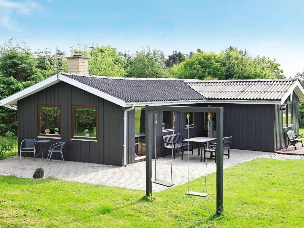 un grand hangar noir avec une table et des chaises dans l'établissement 5 person holiday home in L kken, à Løkken