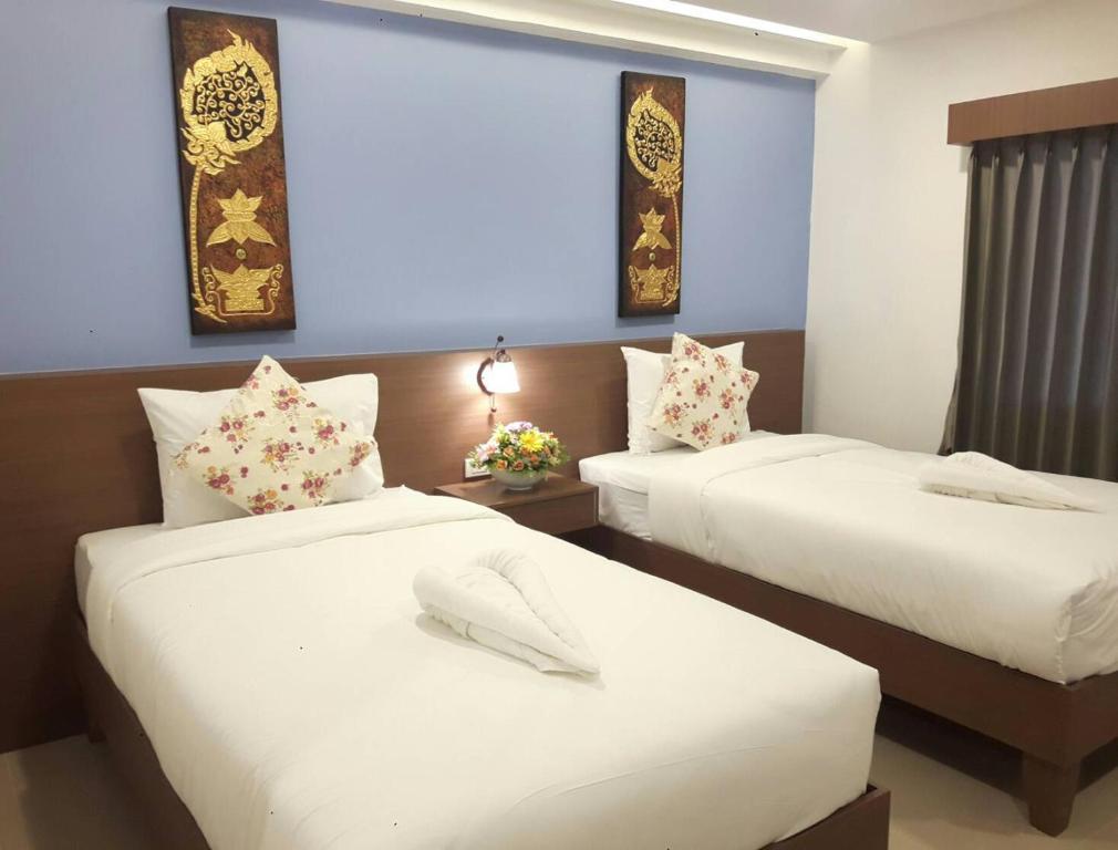 A twin room with two beds, blue accent wall, and curtained window.