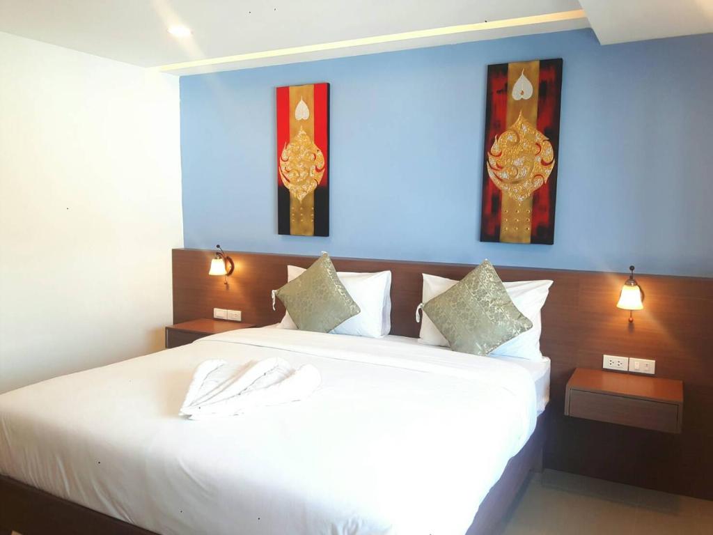 A double bed in a blue-accented room with bedside lighting and Thai-style artwork.