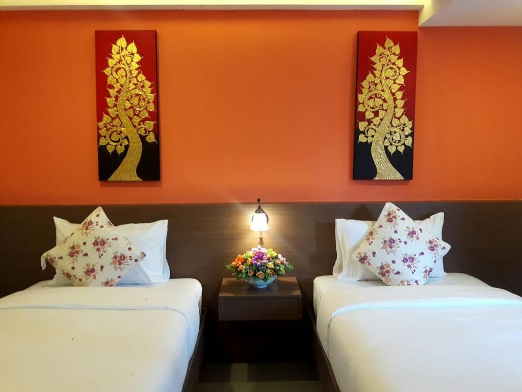 A compact twin room with orange walls, two beds, and a central bedside table.