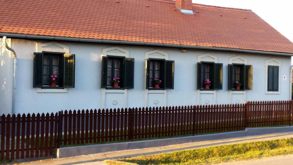 una casa blanca con ventanas negras y una valla en Szentgyörgyvölgy Vendégház Őrség, en Szentgyörgyvölgy