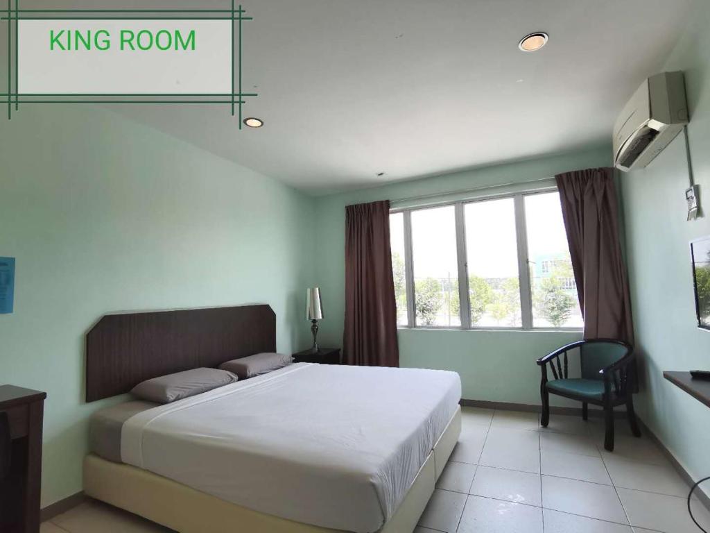 ein Schlafzimmer mit einem Kingsize-Bett und einem Stuhl in der Unterkunft GS BERA HOTEL SDN BHD in Kampong Kerayong