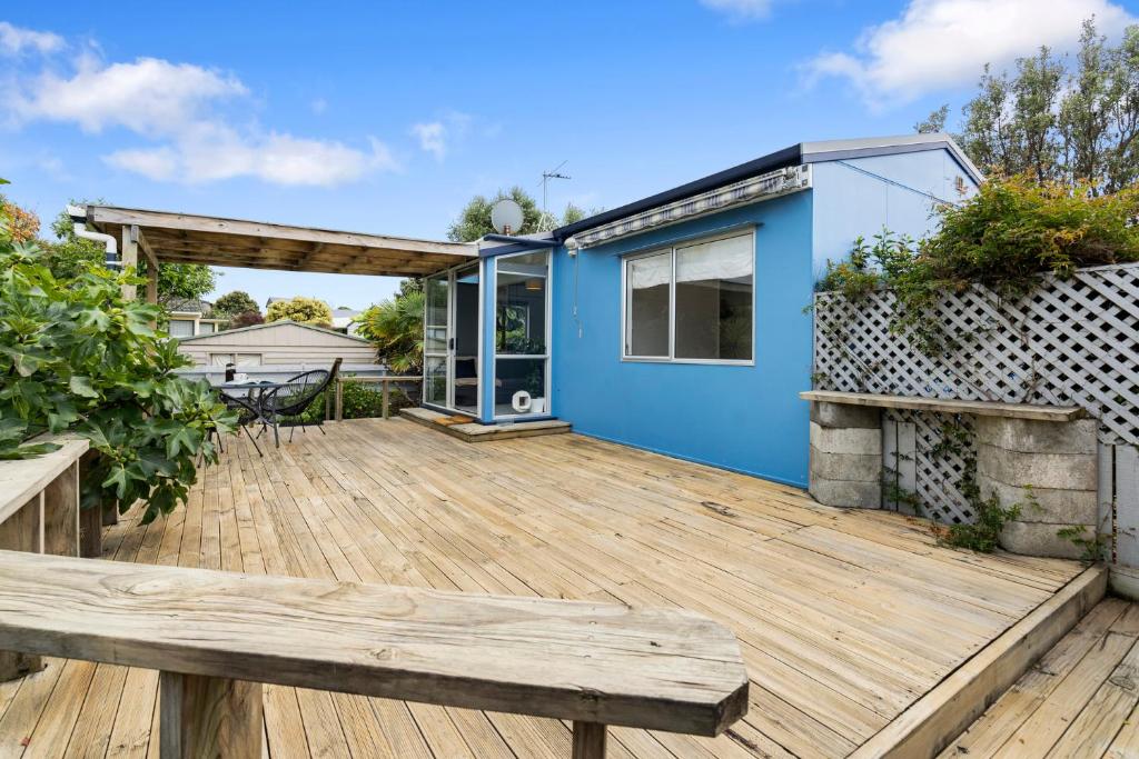 a large deck with a blue house at The Wee Blue Bach - Waikanae Beach Holiday Home in Waikanae