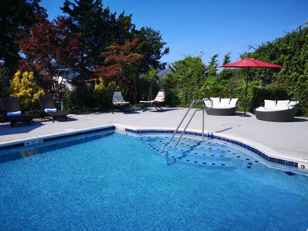 uma piscina com cadeiras e um guarda-sol em Bay Watch Hotel and Marina em Hampton Bays