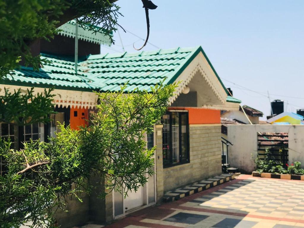 una pequeña casa con techo verde en Mountain View cottage, en Ooty