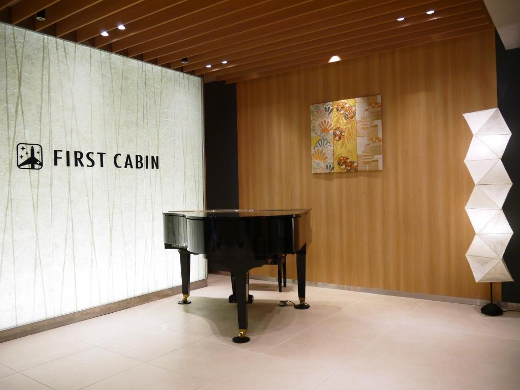 a piano in a room with a first celium sign at First Cabin Kansai Airport in Izumi-Sano