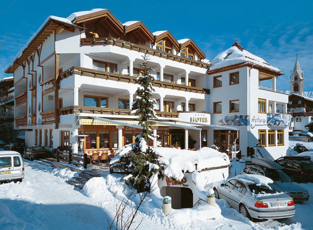 a large snow covered building with cars parked in front of it at Hotel Astoria in Serfaus