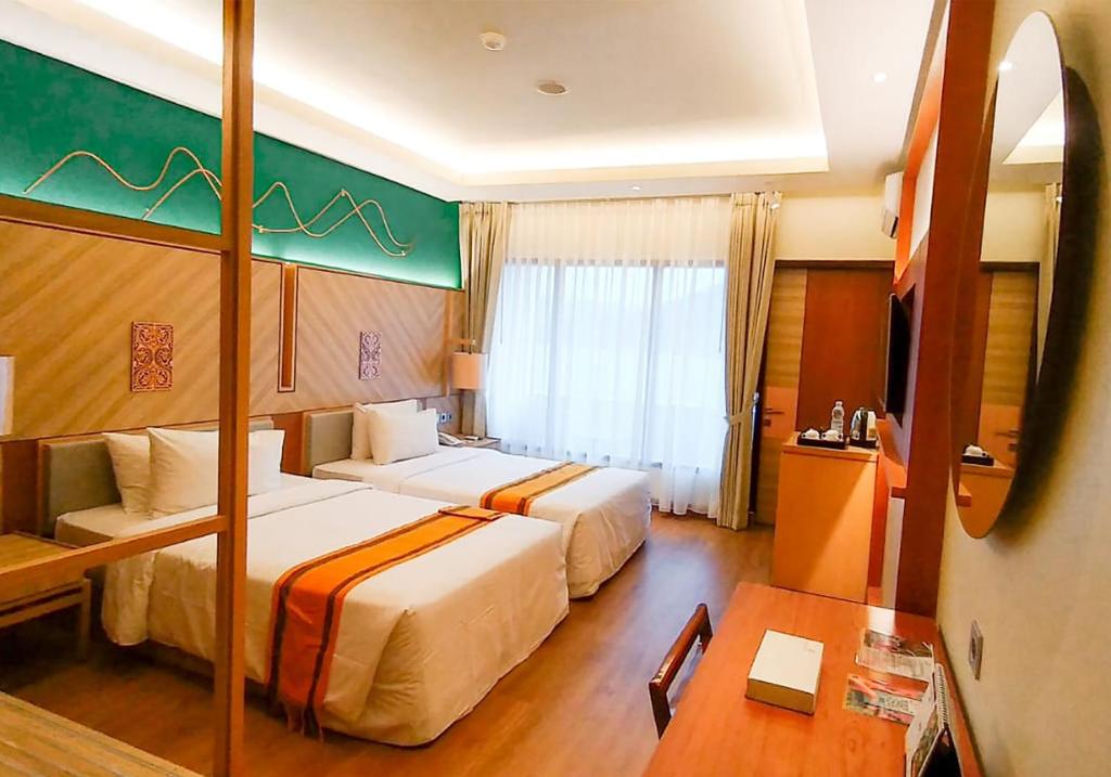 um quarto de hotel com duas camas e uma mesa em Khas Parapat em Parapat