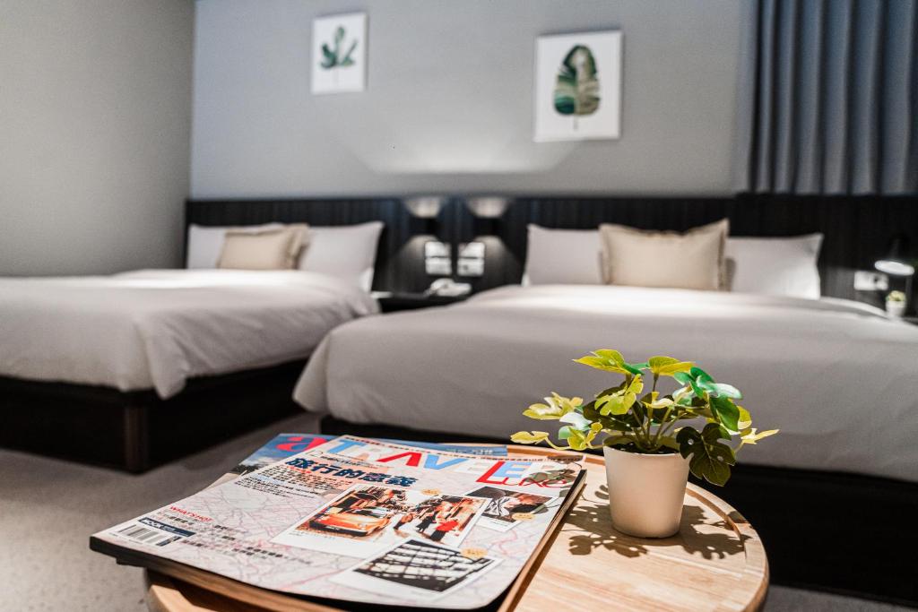 a hotel room with two beds and a table with a plant at ZZINN,penghu in Magong