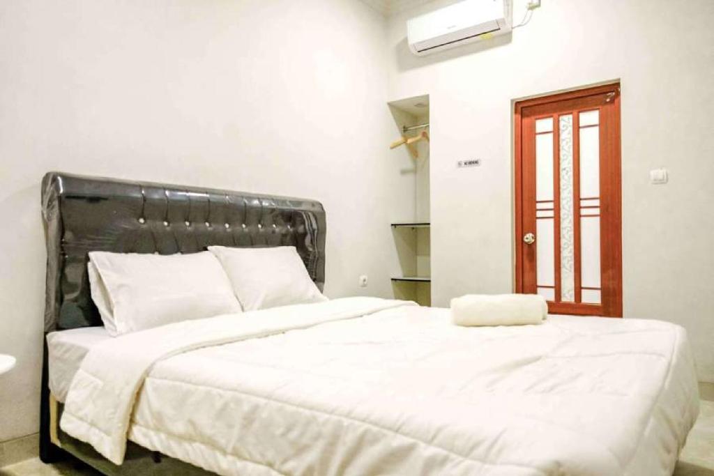 sypialnia z dużym łóżkiem z białą pościelą w obiekcie Rudi Rooms near Stasiun Cikarang Mitra RedDoorz w Dżakarcie