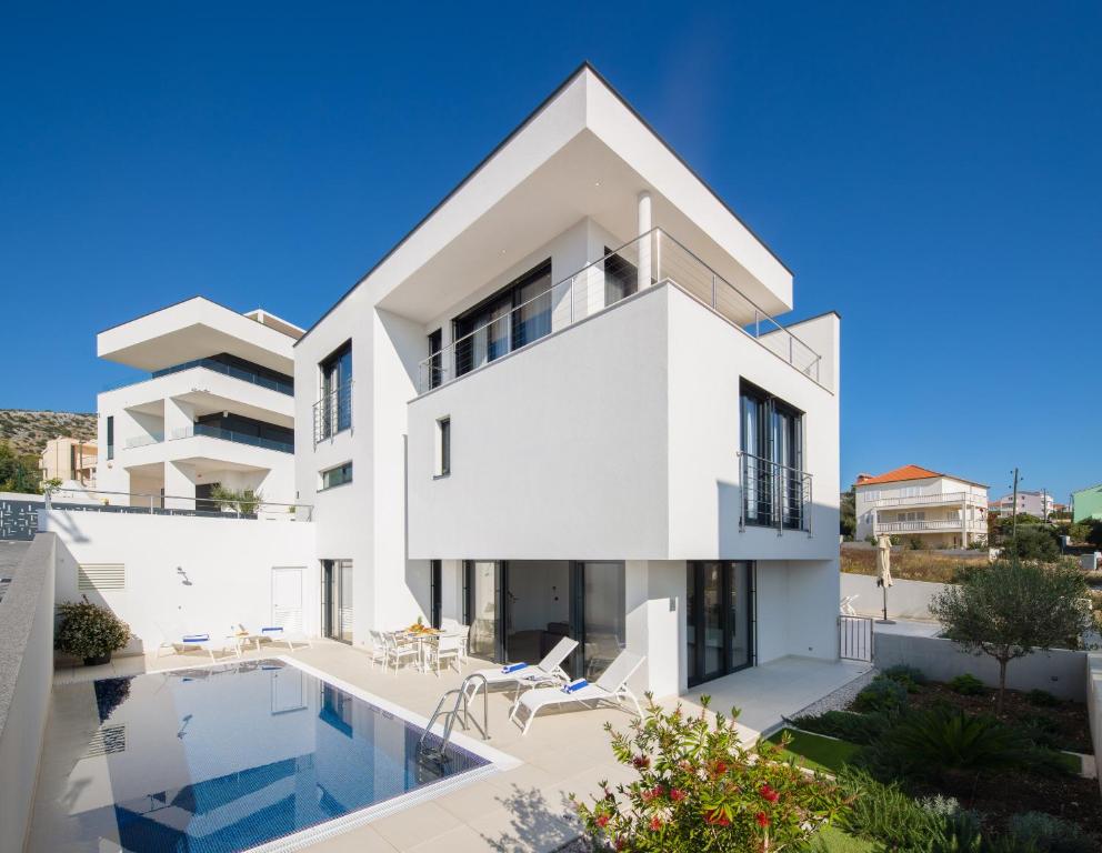 a large white house with a swimming pool at Villas Baotić in Seget Vranjica