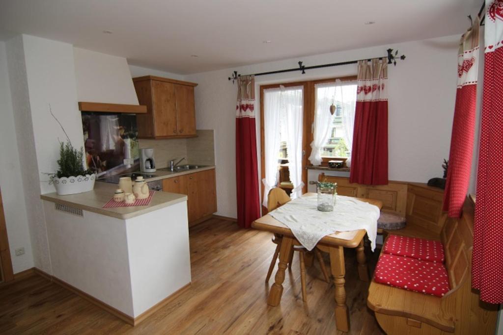 a kitchen with a table and a small kitchen with red curtains at Ferienwohnungen Bodnereck in Schönau am Königssee