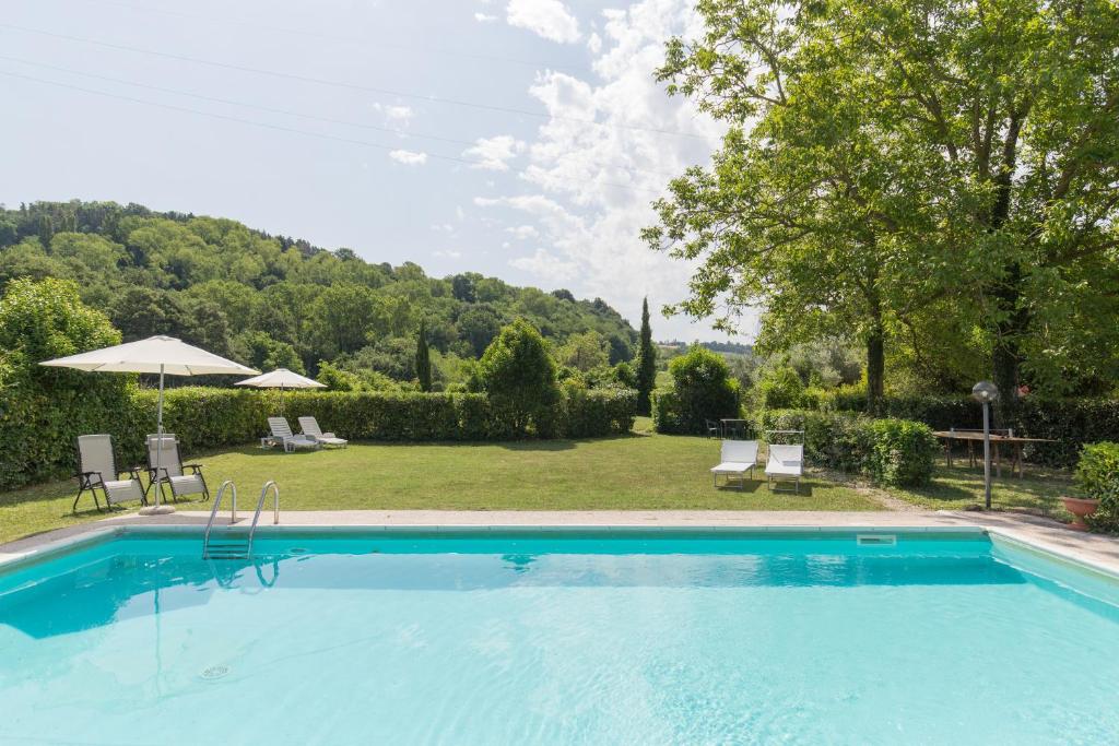 a swimming pool in a yard with chairs and an umbrella at Agriturismo L'Esinante in Cupramontana