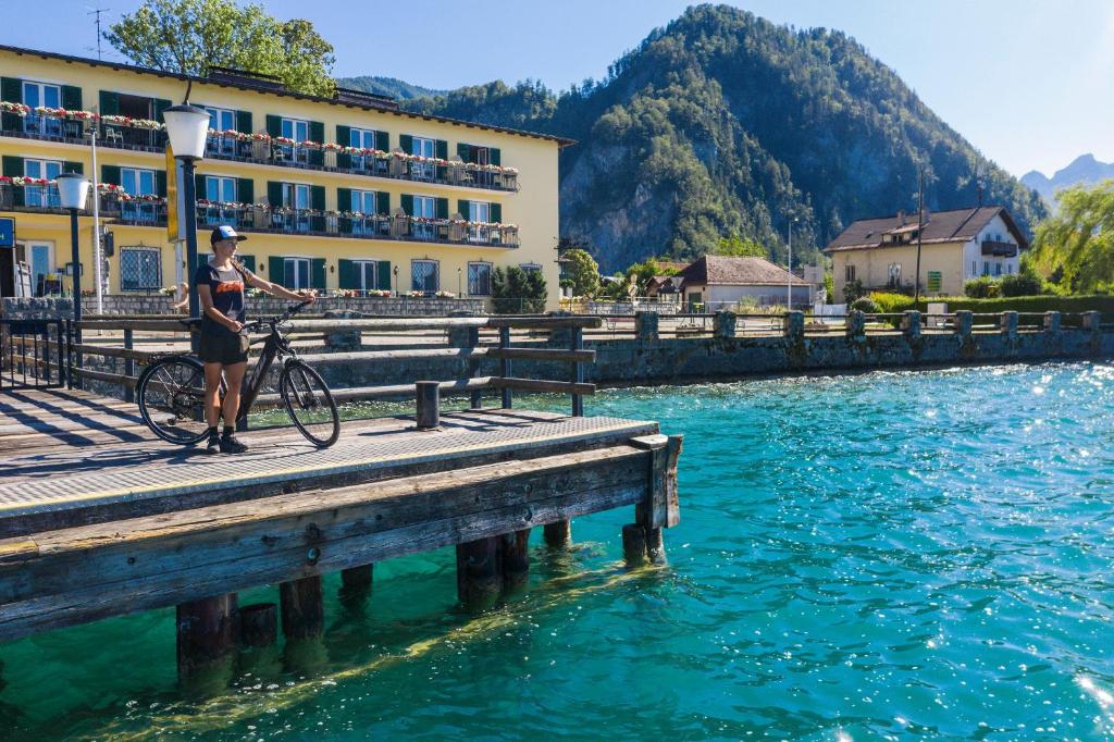 a person with a bike on a dock next to the water at See-Hotel Post am Attersee in Weissenbach am Attersee