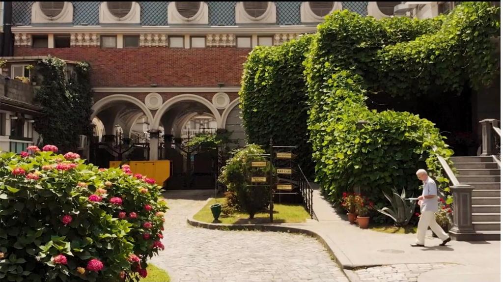 Un uomo che cammina in un giardino in un edificio di Boutique Hotel O. Galogre a Batumi