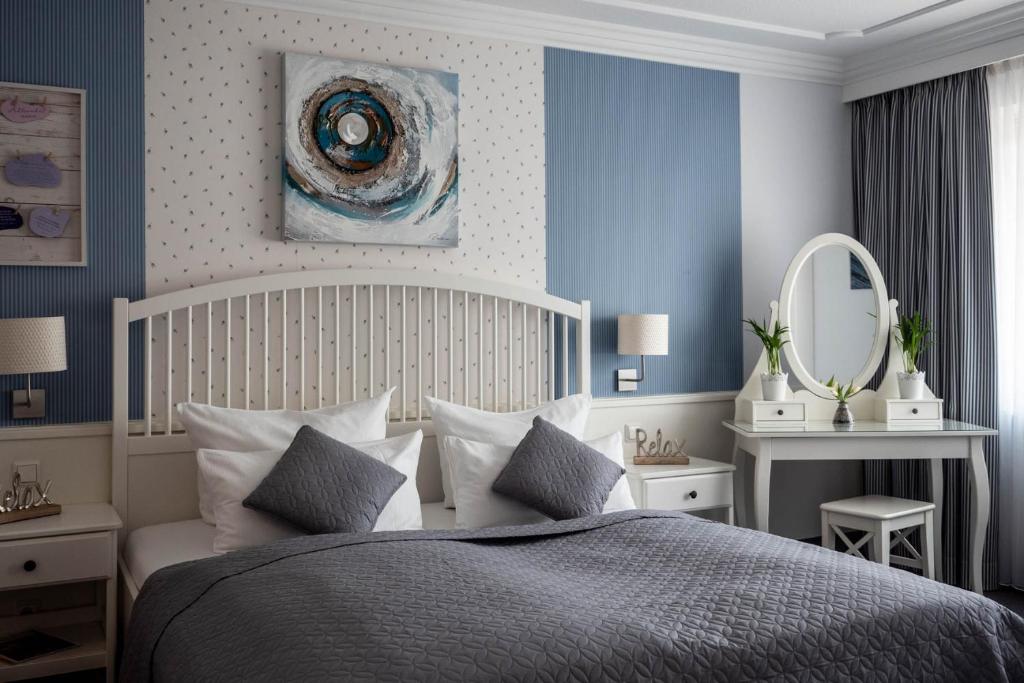 
a bedroom with a bed, a dresser, and a lamp at Garni Hotel & Appartements Nordstrand in Nordstrand
