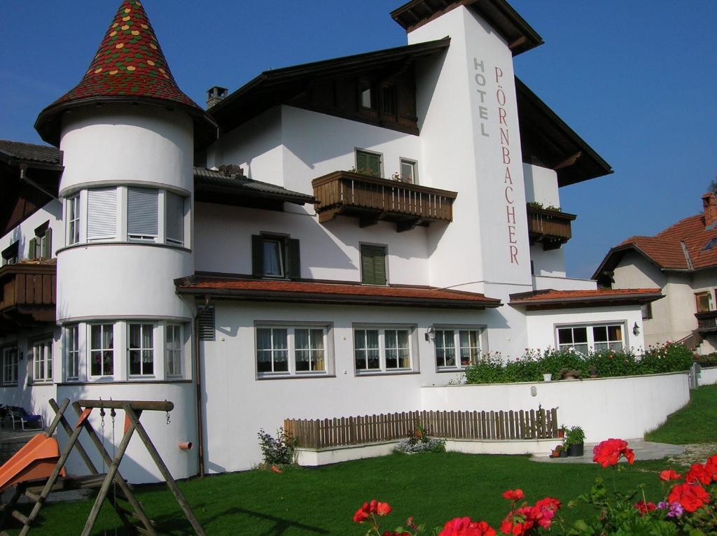 a white house with a red roof and a white clock tower at Hotel Pörnbacher in Valdaora