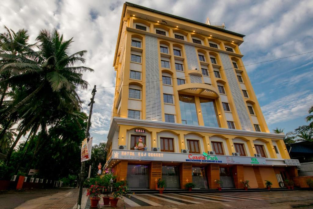 un grand bâtiment jaune avec un palmier devant lui dans l'établissement Hotel Raj Resort, à Madgaon