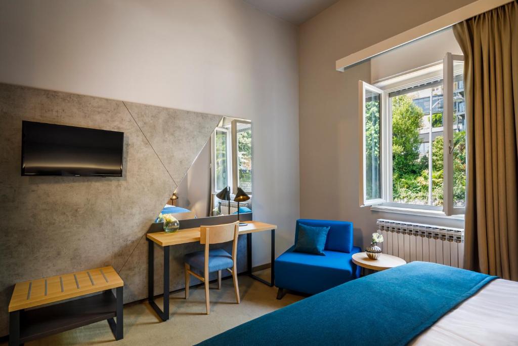 a hotel room with a bed and a table and a blue chair at Hotel Istra - Liburnia in Opatija