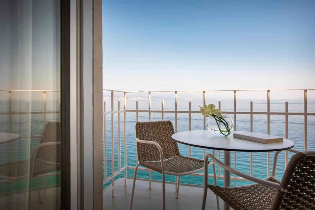 a table and chairs on a balcony with a view of the ocean at Hotel Istra - Liburnia in Opatija