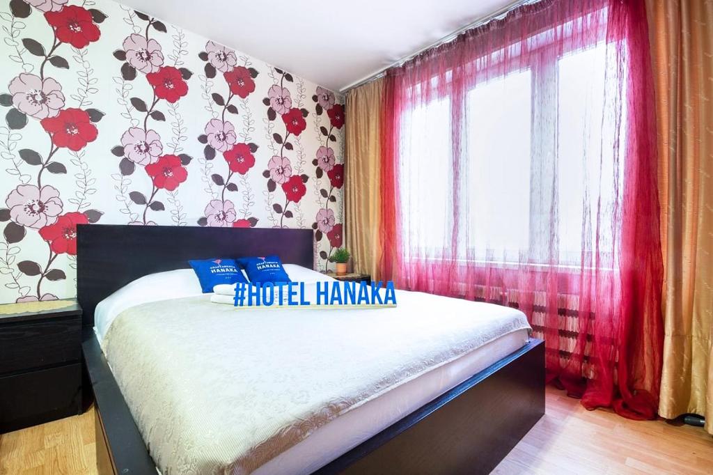 モスクワにあるApartment Hanaka Shchelkovskoye 77のベッドルーム1室(ベッド1台付)、花の咲く窓が備わります。