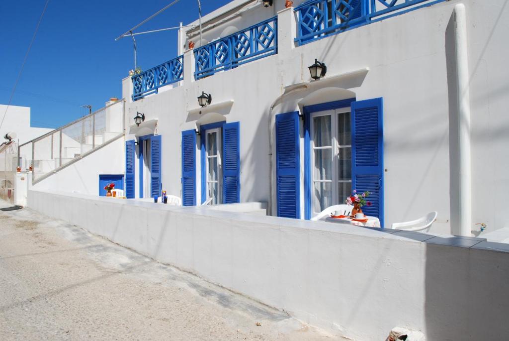 ein weißes Gebäude mit blauen Fensterläden darauf in der Unterkunft To Steno in Kamarai