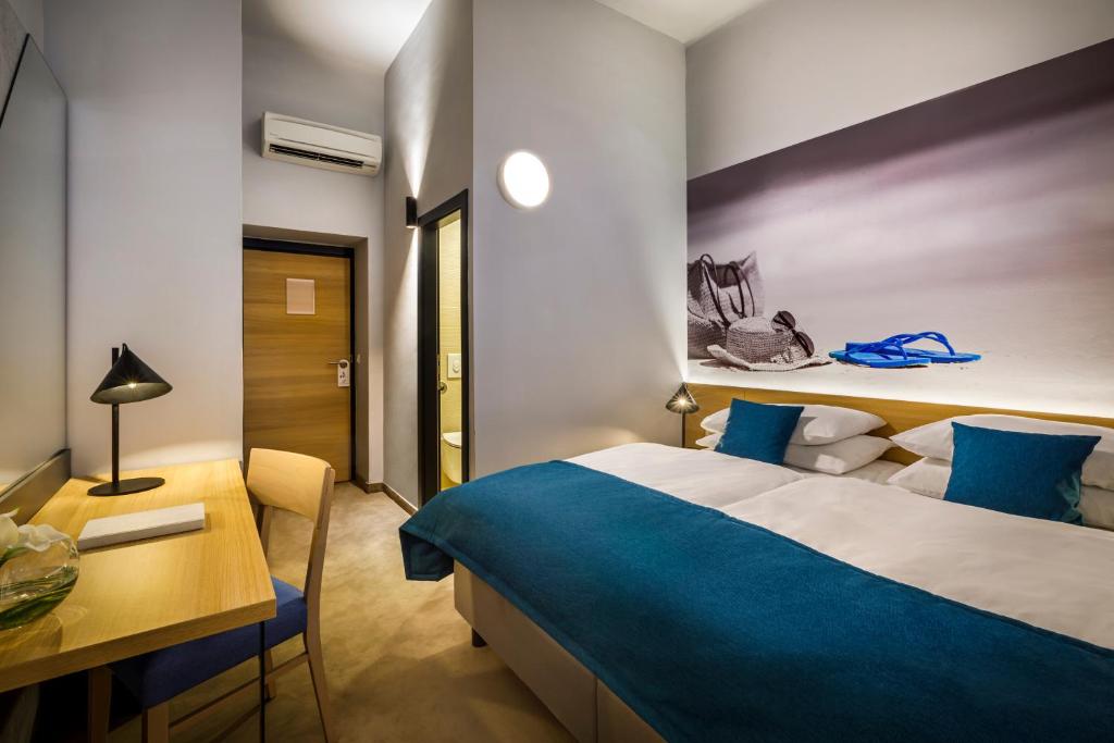 a hotel room with a large bed and a desk at Hotel Istra - Liburnia in Opatija