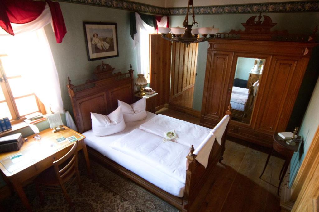 Klausenhof في Bornhagen: غرفة نوم بسرير كبير مع مكتب ومرآة