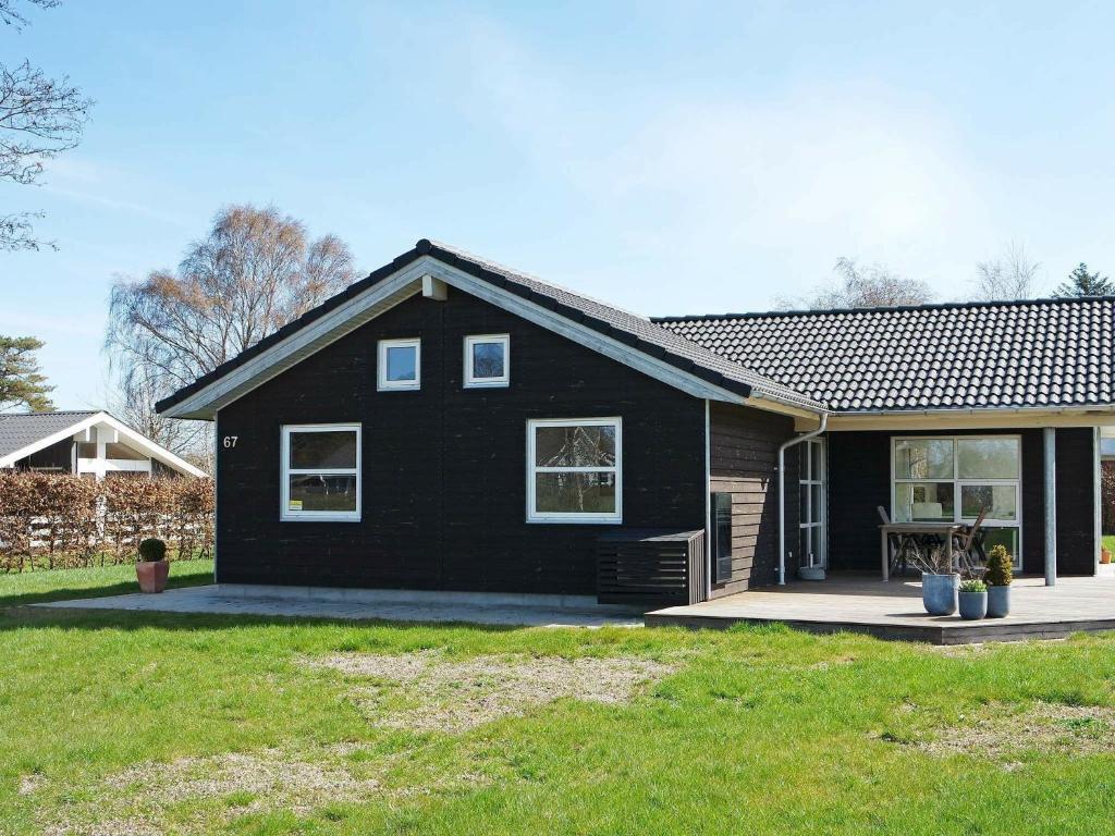 ein schwarzes Haus mit einem Garten davor in der Unterkunft Holiday Home Brøndbækken II in Nørre Hurup