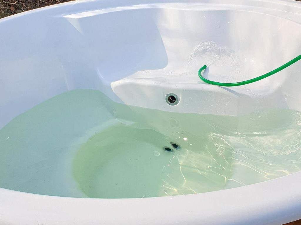 eine weiße Badewanne mit Wasser und einem grünen Schlauch in der Unterkunft 8 person holiday home in Hals in Hals