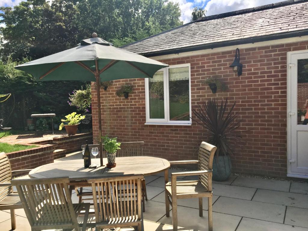 a table and chairs with an umbrella on a patio at Charming 1-Bedroom Apartment near South Downs in Hailsham