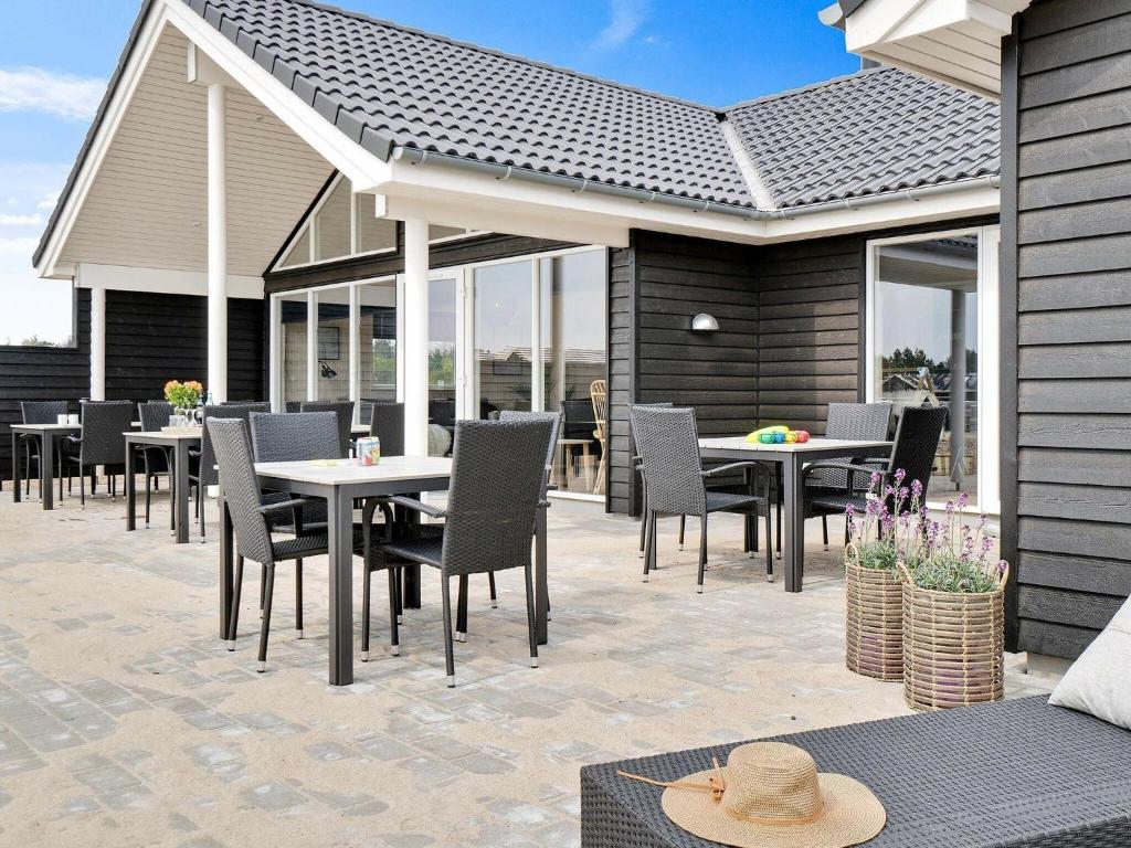 een patio met tafels, stoelen en ramen bij 20 person holiday home in Nørre Nebel in Nørre Nebel