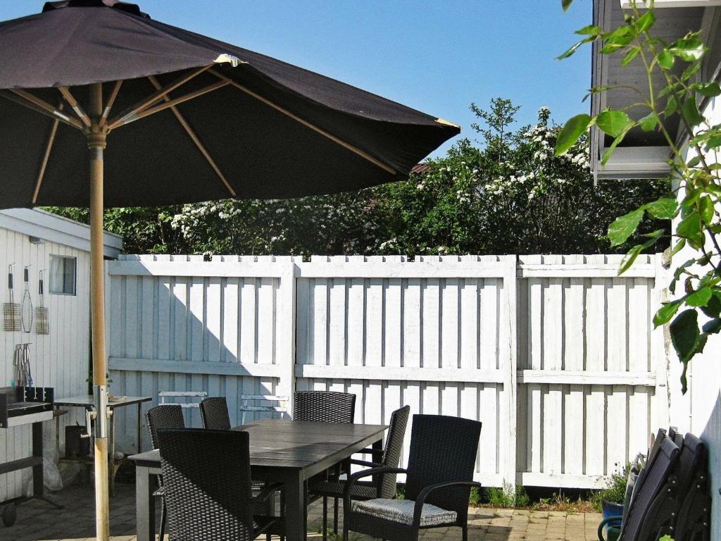 een tafel en stoelen met een parasol op een patio bij Three-Bedroom Holiday home in Faxe in Mosebølle