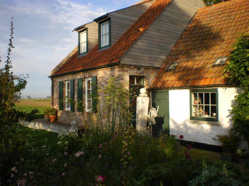 una antigua casa de piedra con techo rojo en Holiday Home Stilleven, en Veurne