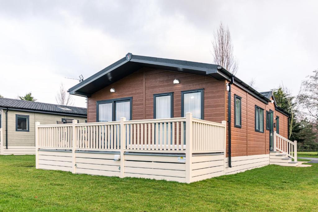 een klein huis met een wit hek in een tuin bij Woodpecker Lodge with Hot Tub in York