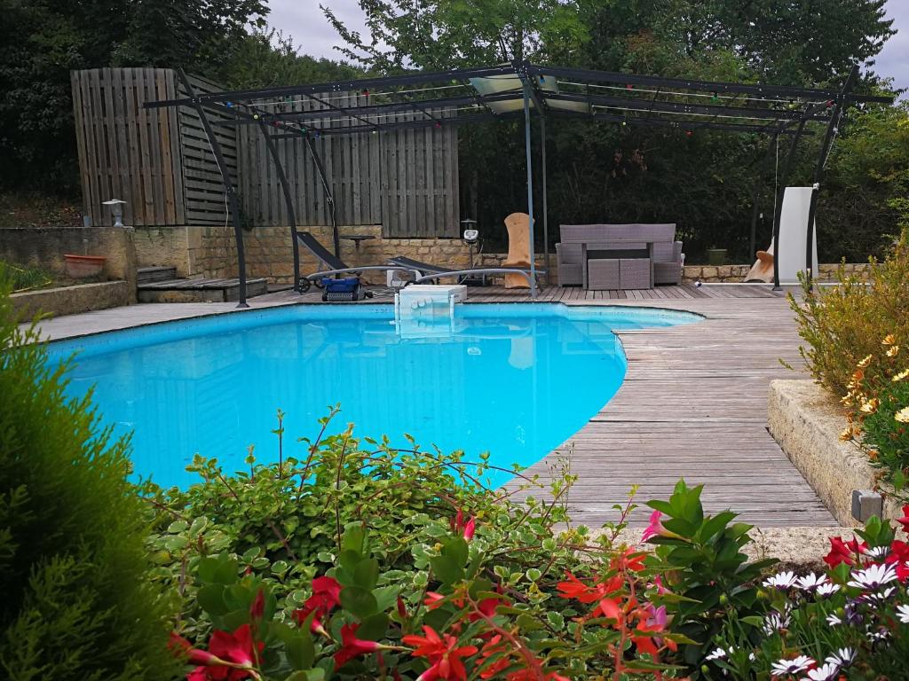 una piscina en un jardín con terraza de madera en La Villa des Coteaux, en Pomport