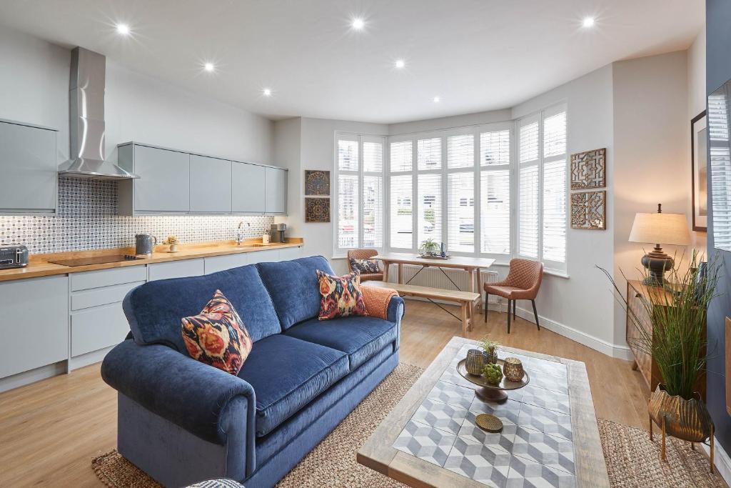 a living room with a blue couch and a kitchen at Host & Stay - Green View in Harrogate