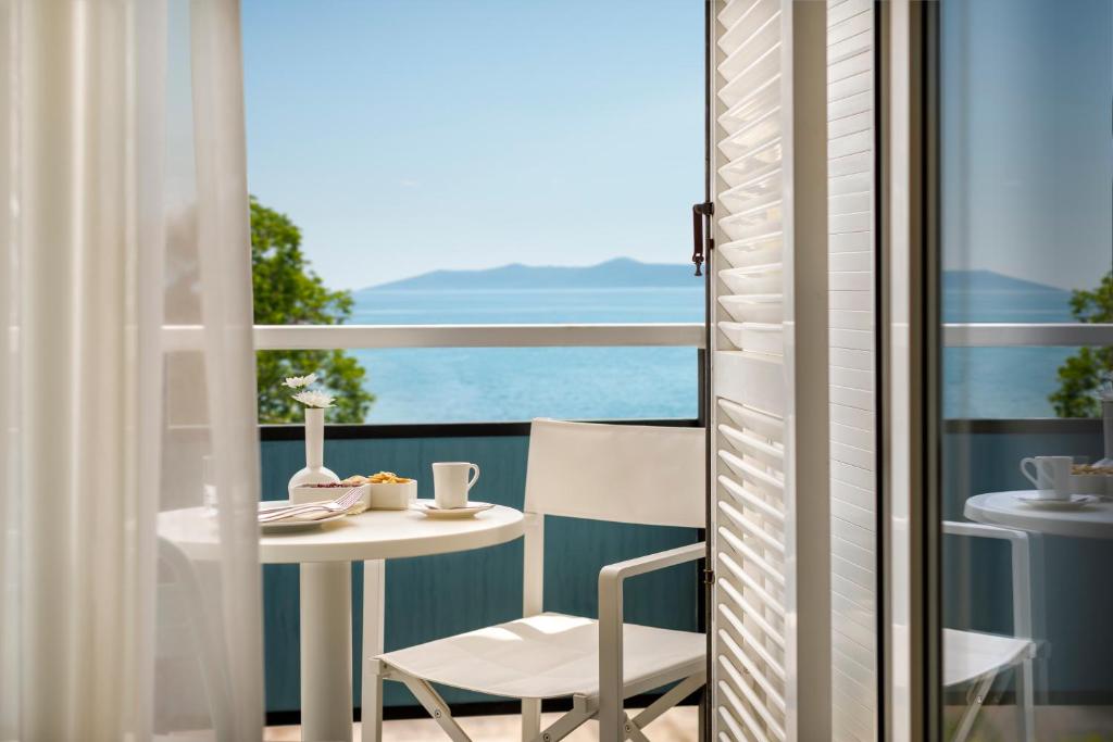 Hotel Marina - Liburnia في موتشينيسكا دراغا: شرفة مع طاولة وكراسي وإطلالة على المحيط