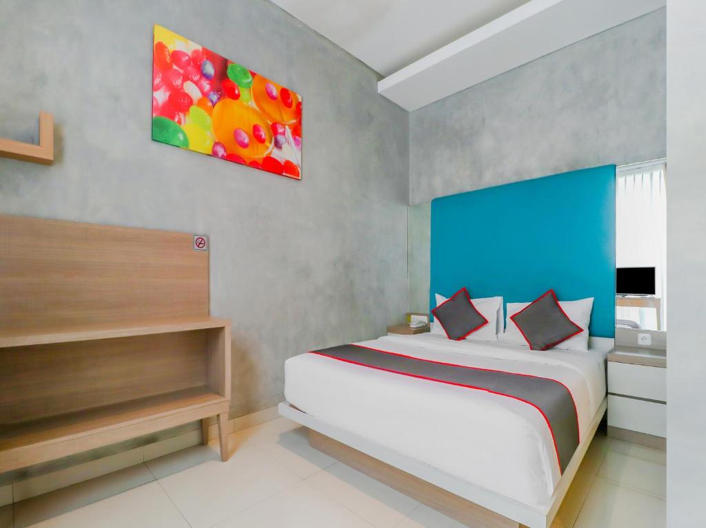 a bedroom with a bed and a painting on the wall at Super OYO Collection O 31 The Batik Bed And Coffee Bandung in Bandung