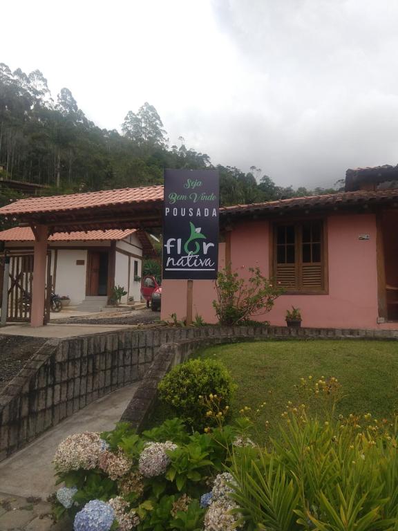 a building with a sign in front of a yard at Pousada Flor Nativa in Brejetuba