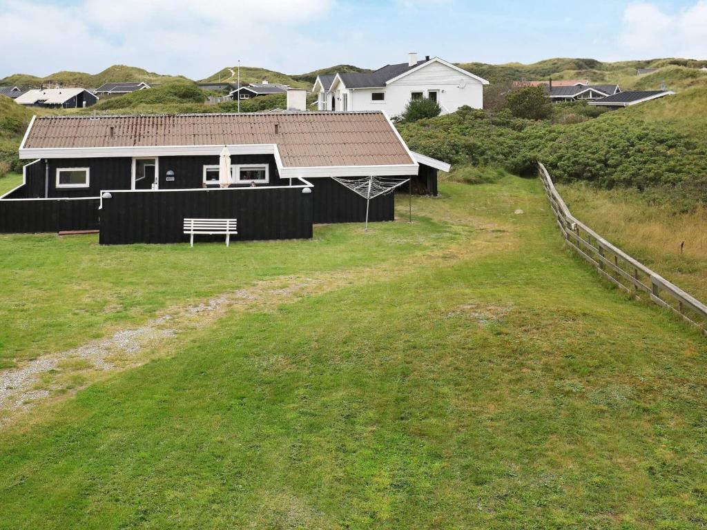 ein Haus mit einer Bank auf einem Grasfeld in der Unterkunft Seaside Serenity in Blokhus-By Traum in Blokhus