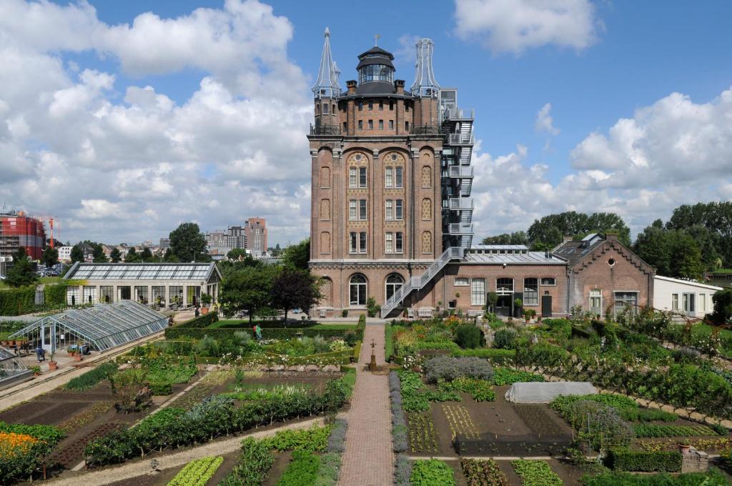 un grand bâtiment avec une tour de l'horloge et un jardin dans l'établissement Villa Augustus, à Dordrecht