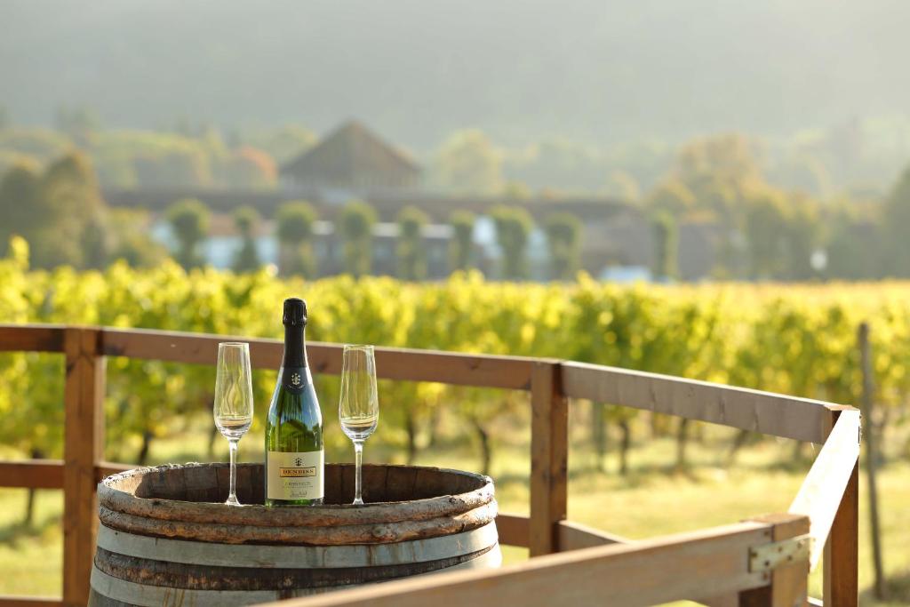 een fles wijn en twee glazen op een vat bij Denbies Vineyard Hotel in Dorking